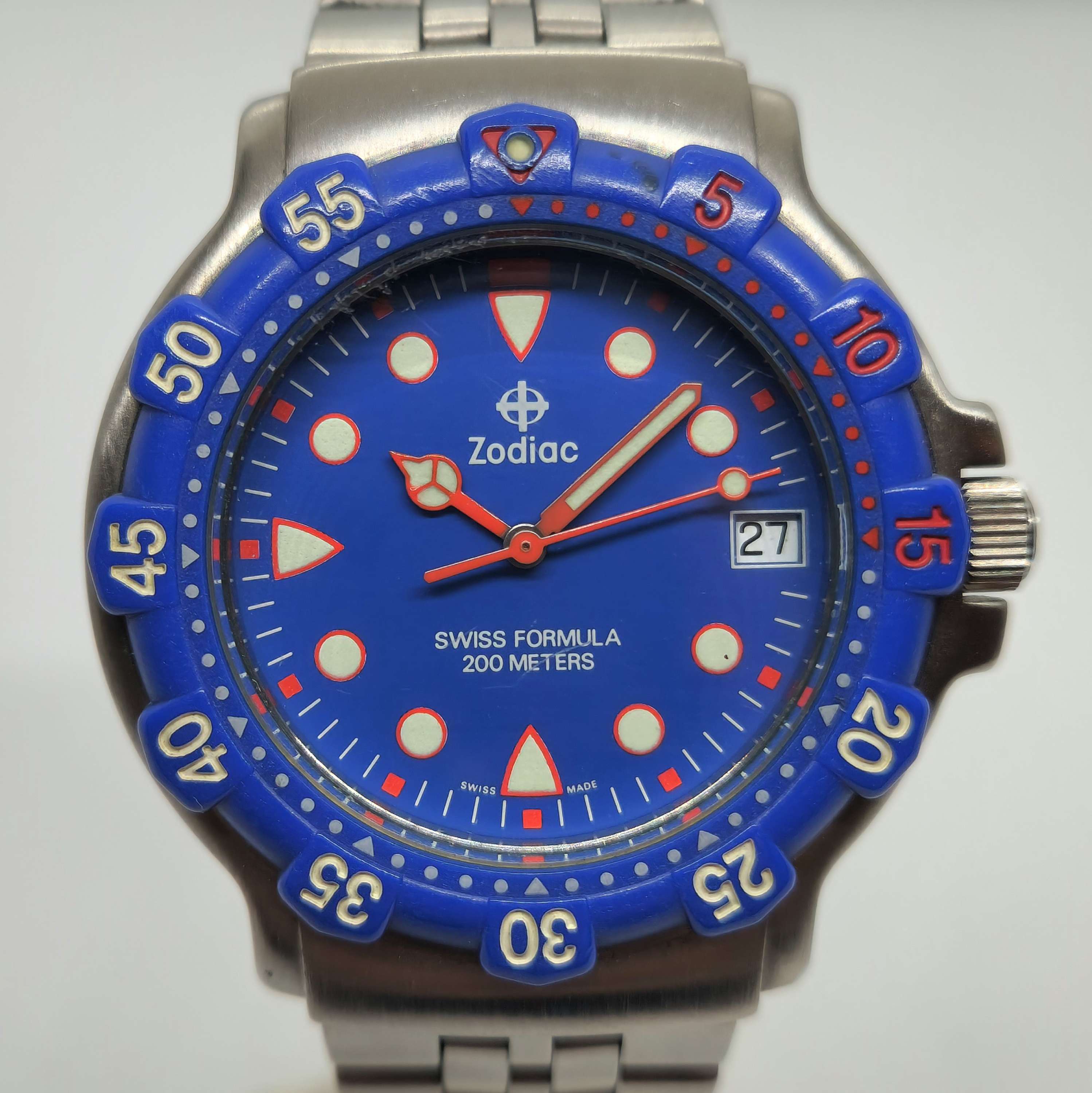 Reloj Zodiac Swiss Formula de acero con bisel azul y agujas rojas, 200 metros, en Joyería Recoleta.